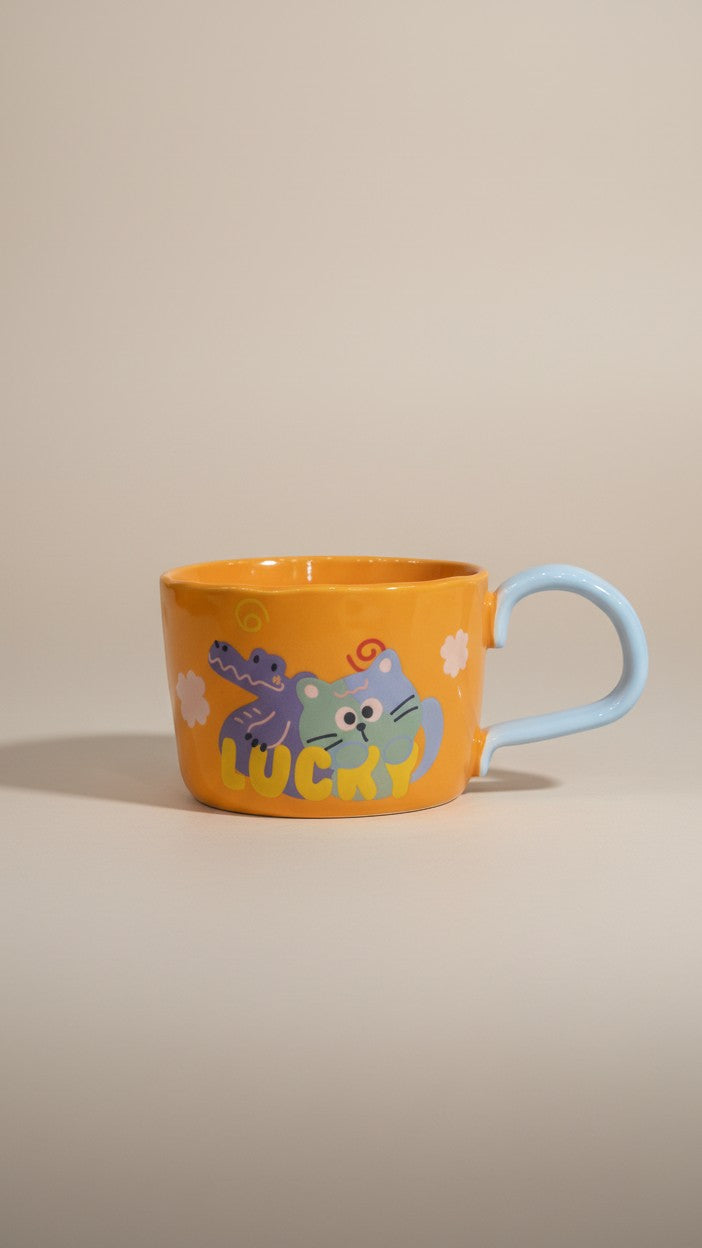 Asoula orange ceramic mug with cute cartoon cat and alligator design, light blue handle.