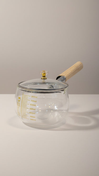 Asoula clear glass saucepan with wooden handle and lid, featuring ml markings for precise cooking.